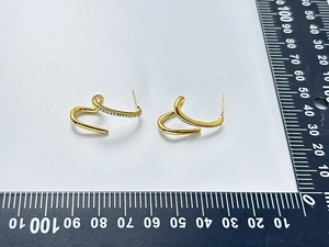 Detail of 18K gold plated irregular curved earrings with zircon inlay and scale ruler
