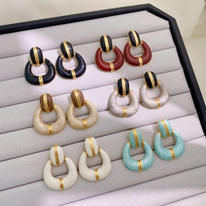 Flat lay of retro enamel geometric hoop earrings in six different colors on velvet tray