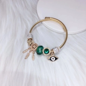 Gold plated bracelet with dreamcatcher, evil eye charms and green crystal beads