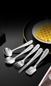 Close-up of brushed stainless steel kid cutlery set with cute smiley faces on handles