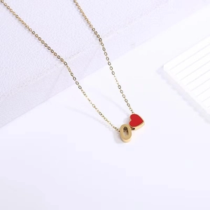 Detailed close-up of gold chain necklace with red heart pendant and number 0 charm