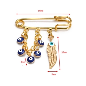 Detail view of gold brooch with blue evil eye beads and feather pendant including dimensions