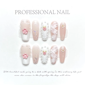 Detail of pink gradient press-on nails with 3D floral accents and pearls