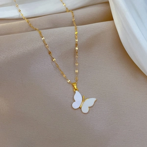 Close-up of gold-plated butterfly pendant with white shell inlay and diamond accents
