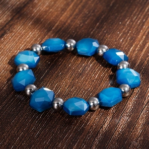 Macro detail of Bohemian beaded bracelet with blue faceted stones and silver beads on wood