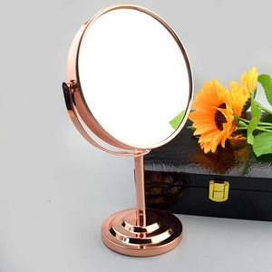 Detalle de espejo de maquillaje de mesa oro rosa con aumento 1:2 y marco de metal giratorio