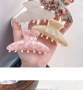 Detail of four colorful acetate hair claws in white, floral, beige and pink patterns