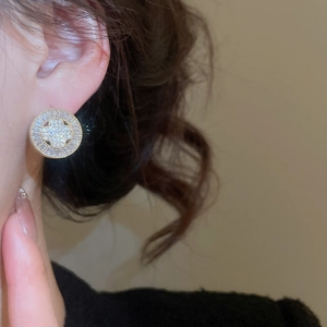Close-up of gold plated round stud earring with cubic zirconia on a female model's ear