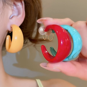 Close-up of colorful acrylic C-shape hoop earrings in glossy yellow, red, blue, and green