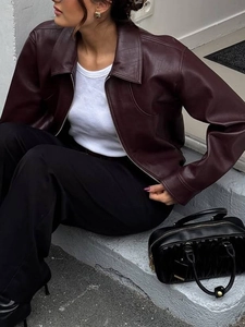 Detail of dark burgundy faux leather jacket collar and zipper texture on outdoor model