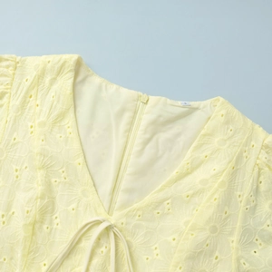 Detail of yellow cotton dress V-neck with eyelet embroidery and back zipper closure