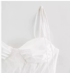 Detail view of white camisole top featuring thin straps and fine ruched chest fabric