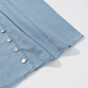 Detailansicht von vier silbernen Metallknöpfen auf hellblauem Denim-Kleiderstoff