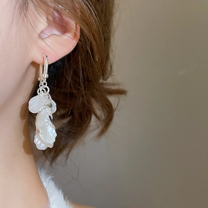 Gros plan de longues boucles d'oreilles à pétales argentés portées par un mannequin