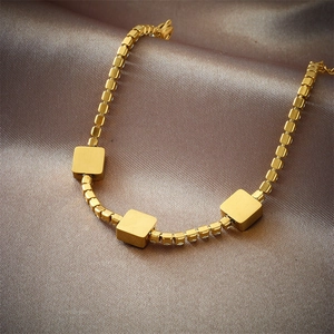 Elegant gold-plated chain bracelet with square emerald pendants on brown silk fabric