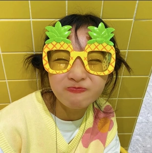 Detail einer lustigen Ananas-Sonnenbrille mit gelbem Rahmen und grünen Blättern