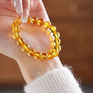 Close-up of translucent citrine beaded bracelet on wrist with warm backlight glow