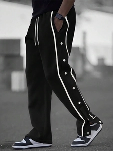 Detail of men's black joggers featuring white side stripes and snap button closures