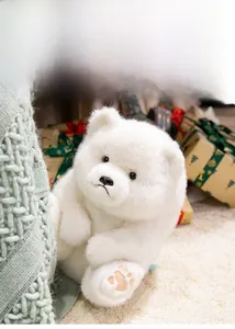 Close-up of white plush teddy bear with embroidered paw prints on green knit blanket