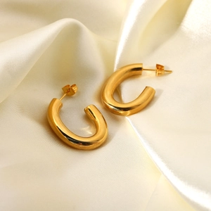 Gros plan détaillé de boucles d'oreilles en U plaquées or 18 carats sur du tissu de soie