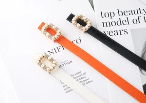 Detail of slim leather belts with pearl rhinestone square buckles in black orange and white