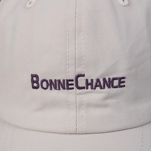 Off-white cotton baseball cap with purple 'BONNE CHANCE' embroidery details