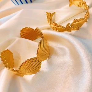 Minimalist gold-plated open cuff bracelet featuring sea shell and fish charms on white silk