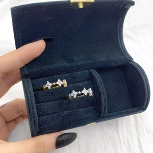 Blue velvet jewelry box holding two gold and silver clover rings with white opals