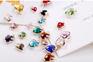 Macro shot of colorful faceted heart-shaped crystal charms with metal edging for jewelry DIY