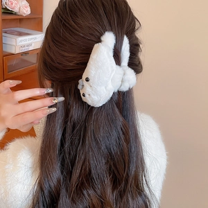 Close-up of white plush seal-shaped hair claw clip on a book background for women