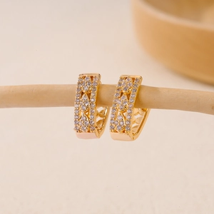 Macro shot of V-shaped gold hoop earrings with zircon stones and hollow floral patterns