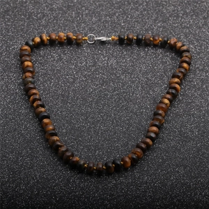 Detail of tiger eye stone beads on a knotted necklace with silver lobster clasp closure