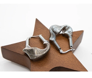 Close-up of silver spiral earrings with a twisted metal design on a wooden star base