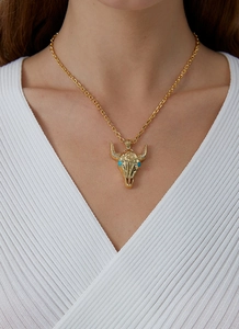 Detail of a gold bull head pendant with blue stone inlay worn on a model's neck