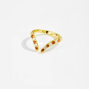 Macro detail of V-shaped gold open ring with orange and clear inlaid gemstones