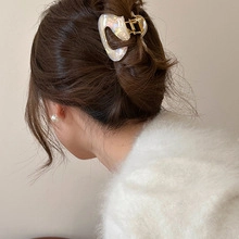 Detail view of a vintage cream heart hair clip worn on wavy hair for a stylish look