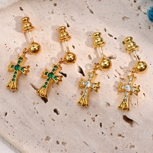Macro shot of vintage gothic cross earrings with green and white zircons on stone