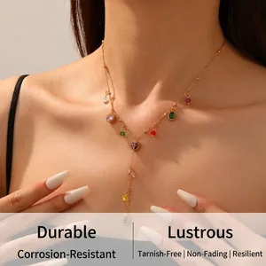 Detail view of a gold Y-shaped necklace with colorful teardrop gemstones on a model