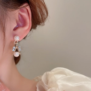 Close-up of elegant gold V-shaped earrings with pearls and crystals worn by a model