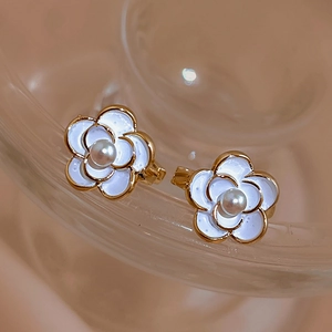Close-up of elegant camellia flower earrings with white petals and gold plated pearl centers