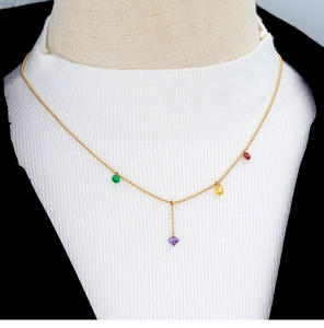 Close-up of a gold chain necklace featuring green, purple, yellow, and red gemstones