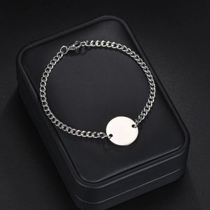 Sleek silver stainless steel curb chain bracelet with a flat circular charm on a black case