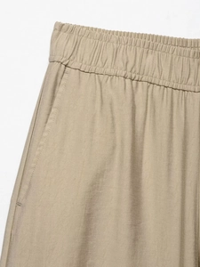 Detail of khaki wide-leg pants showing elastic waistband and side pocket craftsmanship