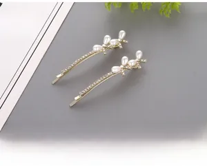 Detail of gold hair clips with sparkling rhinestones and white teardrop pearls in leaf shape