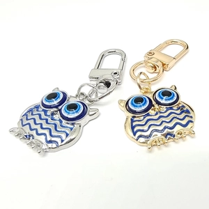 Detail of owl keychains in silver and gold metal with blue evil eye charms