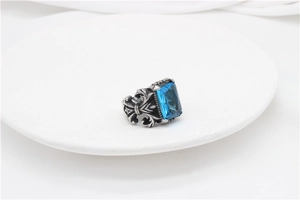 Macro shot of gothic stainless steel ring with rectangle blue gem and fleur-de-lis reliefs