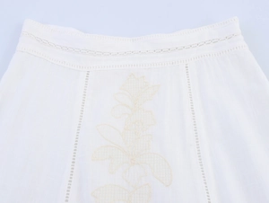 Detailed view of white cotton skirt waist with delicate floral embroidery and lace trim