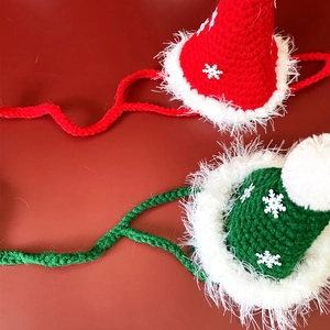 Detail of red and green knitted Christmas hats for pets with snowflake and fur trim