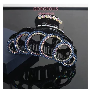 Macro detail of large black hair claw clip with blue and AB crystals on mirror surface