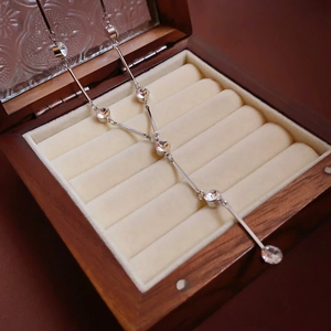Detailed view of silver Y-shaped crystal lariat necklace in a wooden jewelry box